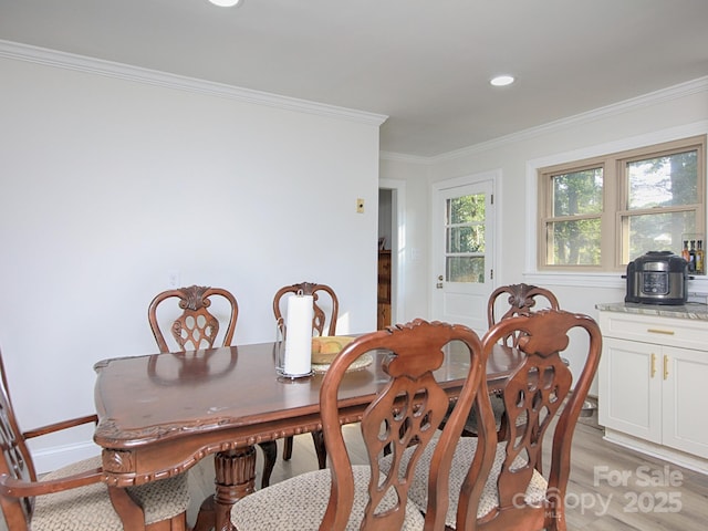 dining space with ornamental molding and light hardwood / wood-style floors