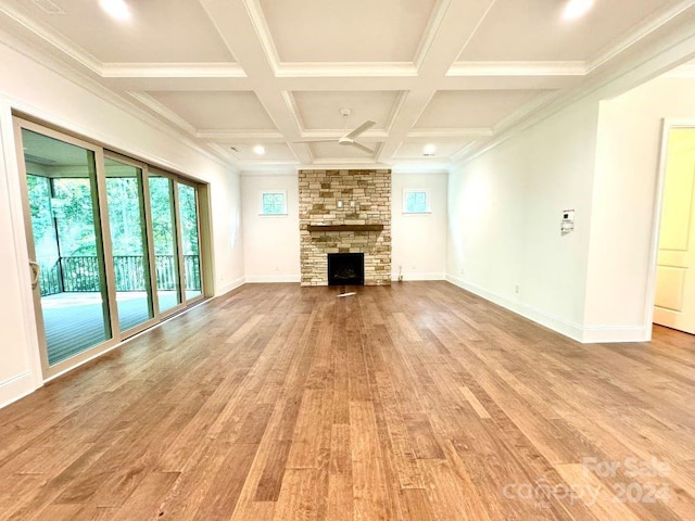 unfurnished living room with ornamental molding, beam ceiling, coffered ceiling, a fireplace, and light hardwood / wood-style floors