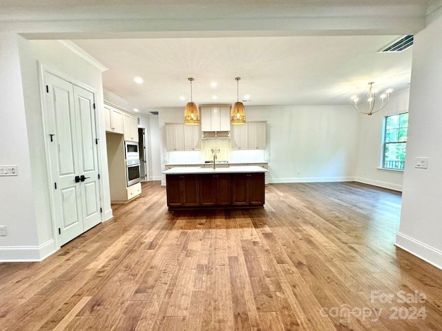 kitchen featuring pendant lighting, light wood-type flooring, a kitchen island with sink, and sink