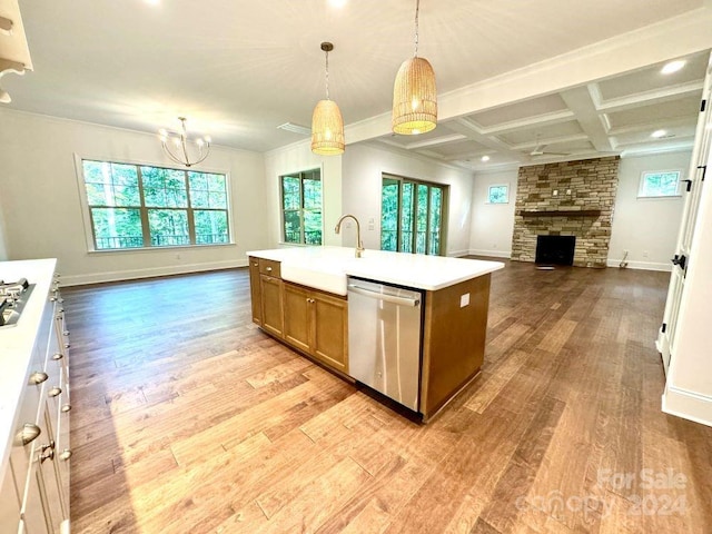 kitchen featuring light wood-type flooring, dishwasher, a center island with sink, and a fireplace