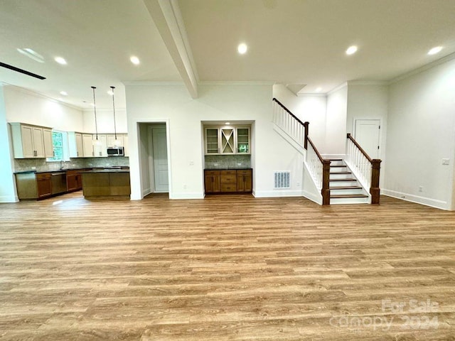 unfurnished living room with light wood-type flooring, ornamental molding, and sink