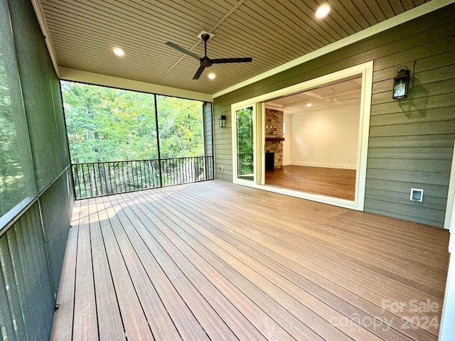 unfurnished sunroom with wood ceiling, a fireplace, and ceiling fan