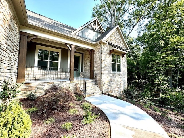 property entrance featuring covered porch, stone siding, and board and batten siding