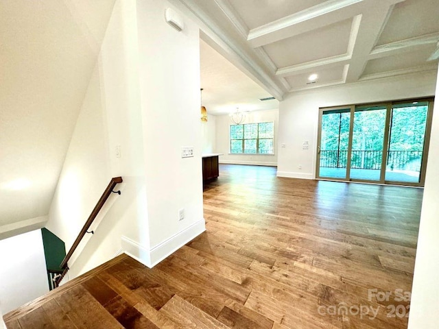 unfurnished room featuring baseboards, coffered ceiling, ornamental molding, wood finished floors, and beam ceiling