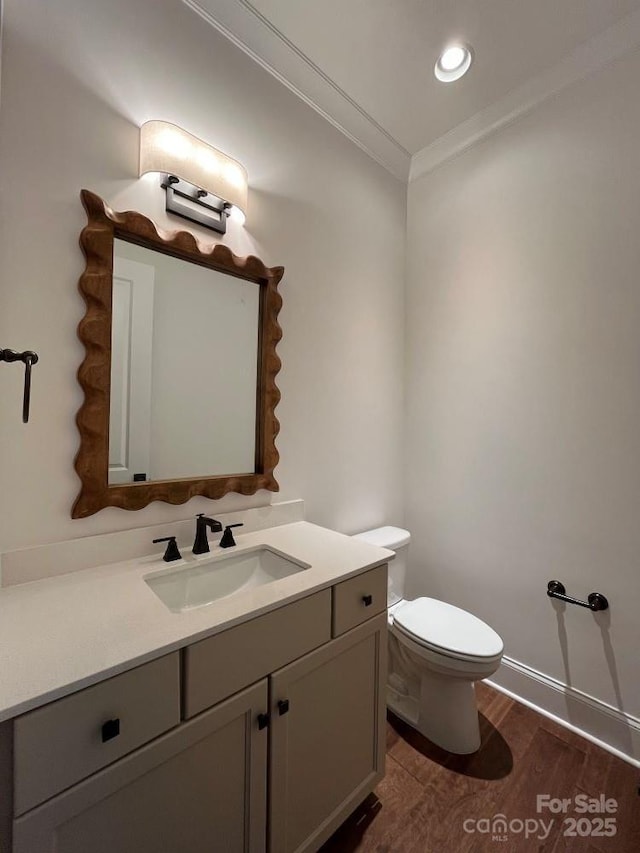 half bathroom featuring crown molding, recessed lighting, toilet, vanity, and wood finished floors