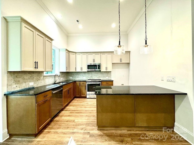 kitchen featuring stainless steel appliances, tasteful backsplash, ornamental molding, a sink, and a peninsula