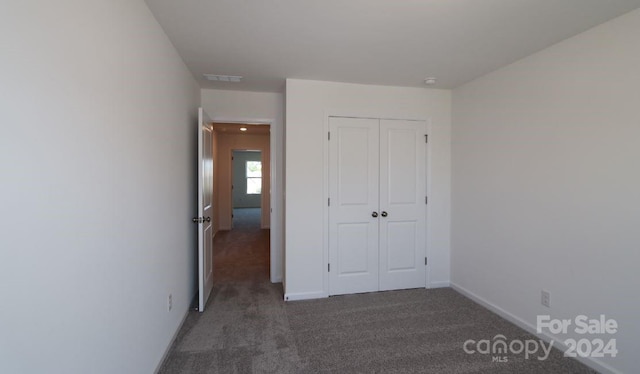 unfurnished bedroom with a closet and dark colored carpet