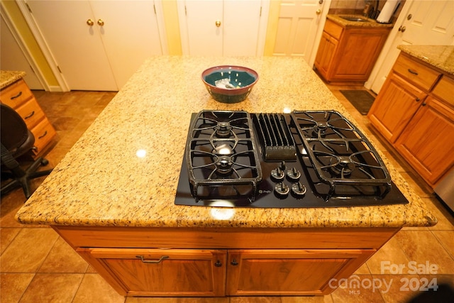 interior details featuring light stone countertops, black gas stovetop, and light tile patterned floors