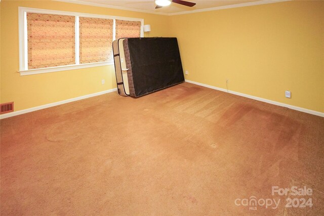 carpeted spare room featuring crown molding and ceiling fan