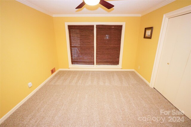 carpeted empty room featuring ornamental molding and ceiling fan