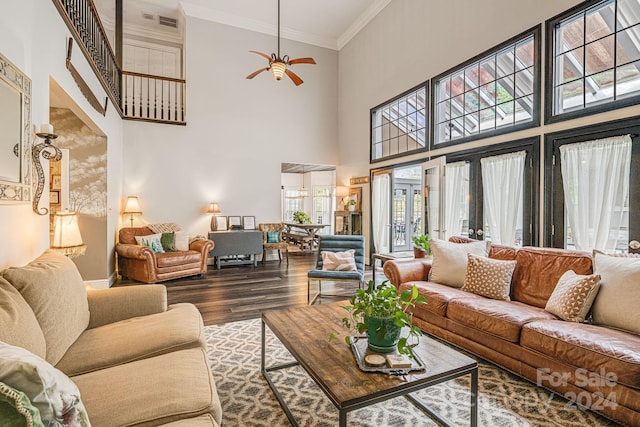 living room featuring ceiling fan, a high ceiling, wood-type flooring, and ornamental molding