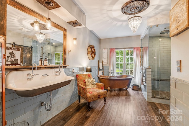 bathroom with hardwood / wood-style floors, tile walls, separate shower and tub, and a notable chandelier