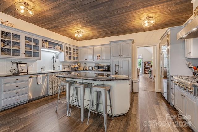 kitchen with wooden ceiling, dark stone countertops, stainless steel appliances, and a kitchen island