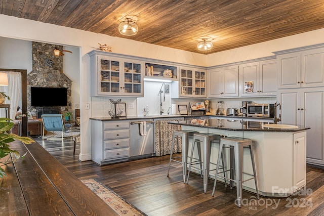 kitchen featuring appliances with stainless steel finishes, a kitchen island, dark stone countertops, a breakfast bar, and gray cabinetry