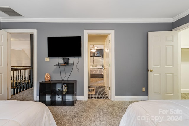 bedroom with crown molding, connected bathroom, and carpet floors