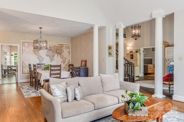 living room featuring a notable chandelier, high vaulted ceiling, hardwood / wood-style floors, and decorative columns