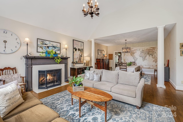 living room with vaulted ceiling, a notable chandelier, hardwood / wood-style flooring, and ornate columns