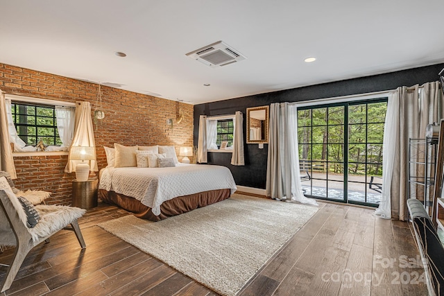 bedroom featuring dark wood-type flooring, brick wall, and access to outside