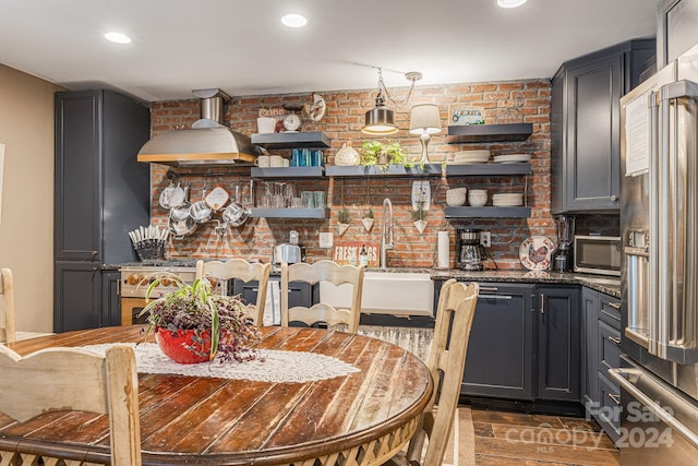 kitchen featuring brick wall, sink, hanging light fixtures, and high end fridge