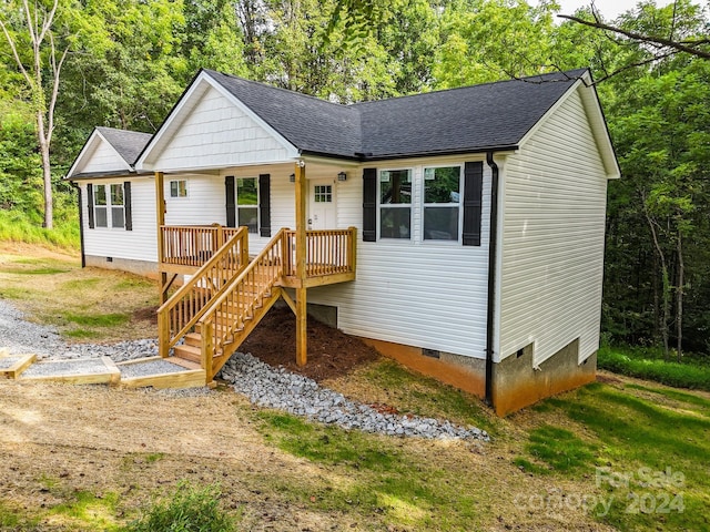 view of front of home with crawl space, a forest view, a shingled roof, and stairs