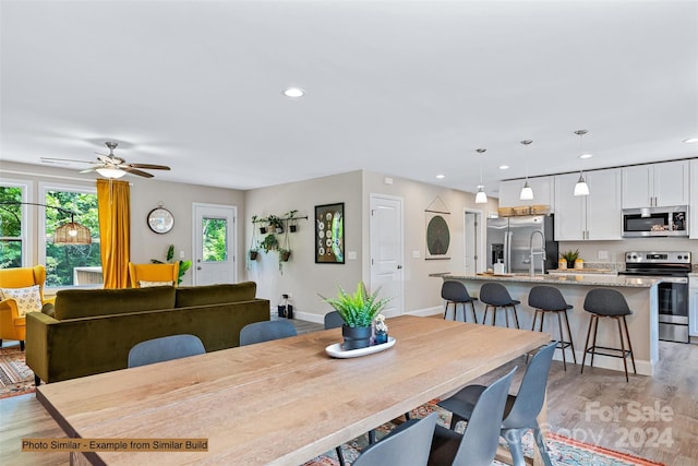 dining space with light hardwood / wood-style floors, ceiling fan, and sink