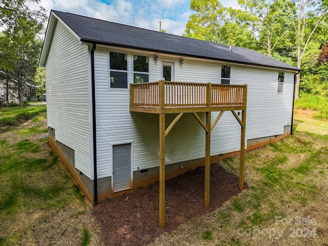 back of house with a deck and a lawn