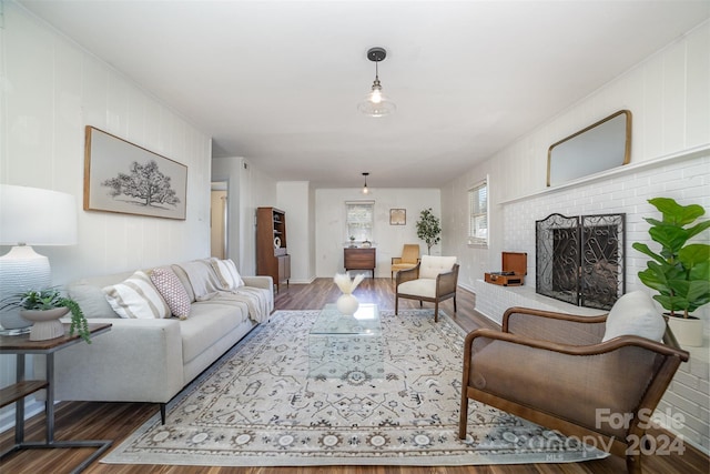 living room with dark hardwood / wood-style flooring and a brick fireplace