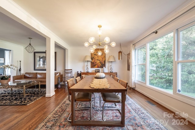 dining space with crown molding, hardwood / wood-style flooring, and a chandelier