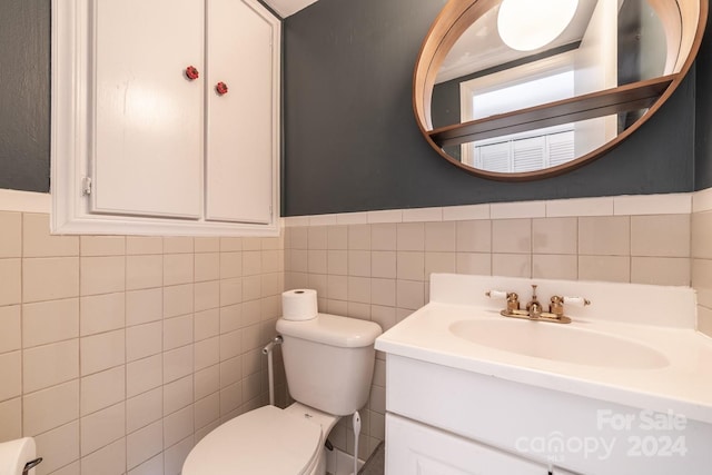 bathroom featuring vanity, toilet, and tile walls