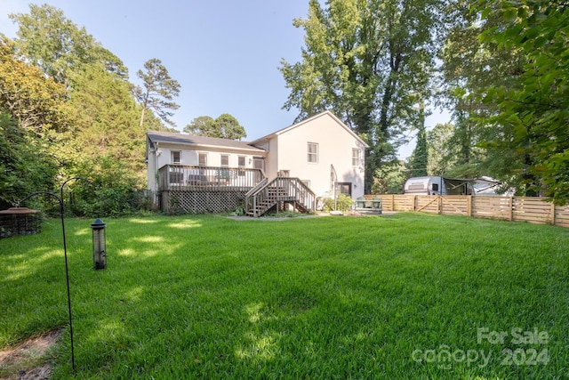 rear view of house featuring a wooden deck and a lawn