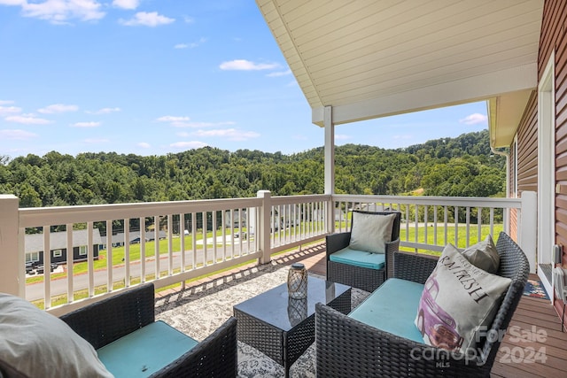 wooden deck with a forest view and outdoor lounge area