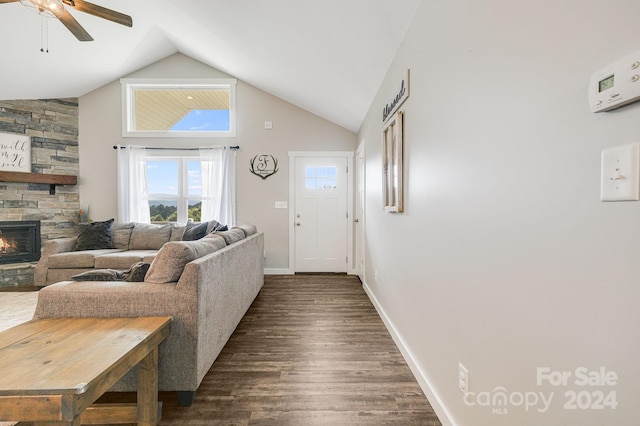 living room featuring dark wood-style floors, a ceiling fan, a stone fireplace, high vaulted ceiling, and baseboards