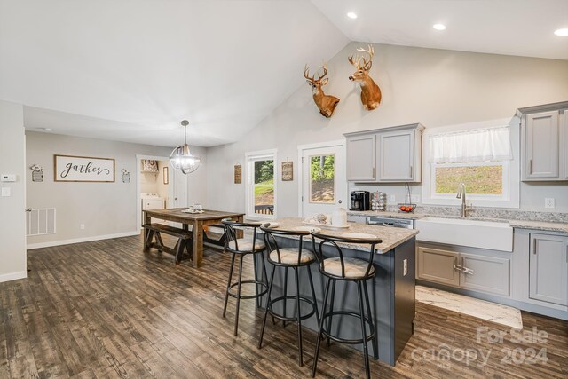 kitchen featuring a breakfast bar, a sink, visible vents, gray cabinets, and dark wood finished floors