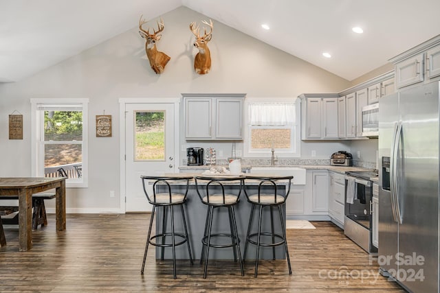 kitchen with dark wood-style floors, a center island, a breakfast bar area, light countertops, and appliances with stainless steel finishes