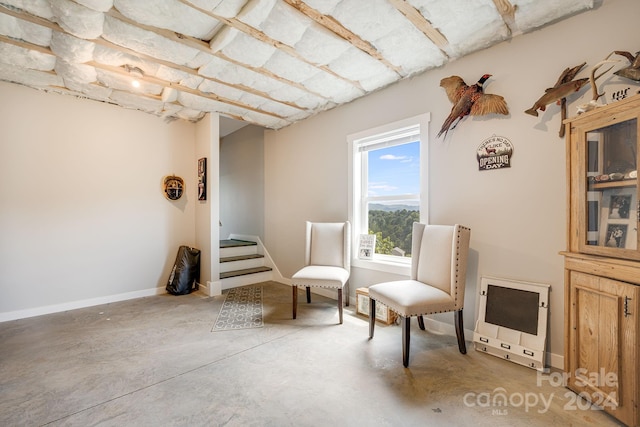 sitting room with heating unit, concrete floors, baseboards, and stairs