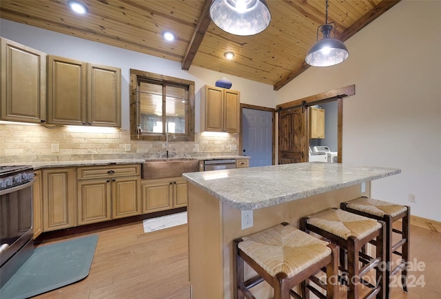 kitchen with decorative backsplash, a barn door, a kitchen bar, and sink