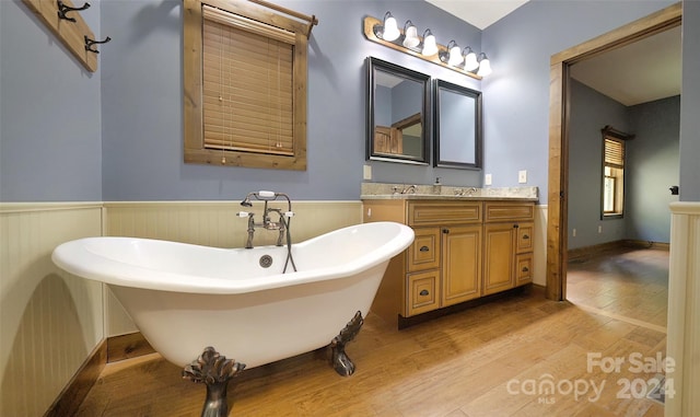 bathroom with vanity, a bath, and wood-type flooring