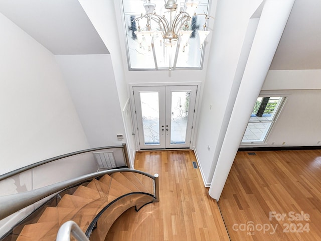 entryway with a towering ceiling, light hardwood / wood-style flooring, and french doors