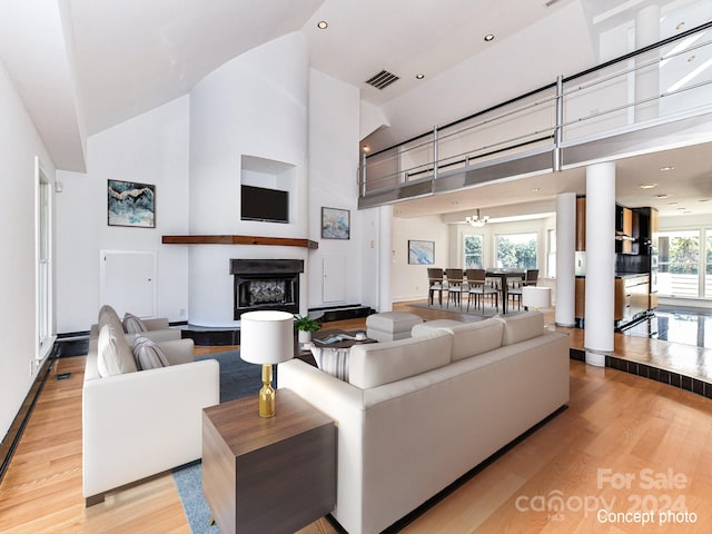 living room featuring a towering ceiling, plenty of natural light, and light hardwood / wood-style floors