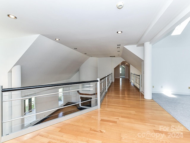 corridor with hardwood / wood-style floors and lofted ceiling