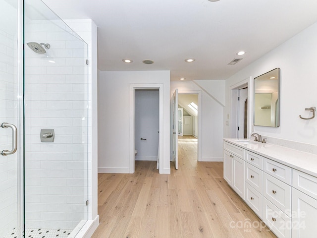 bathroom with toilet, vanity, wood-type flooring, and a shower with door