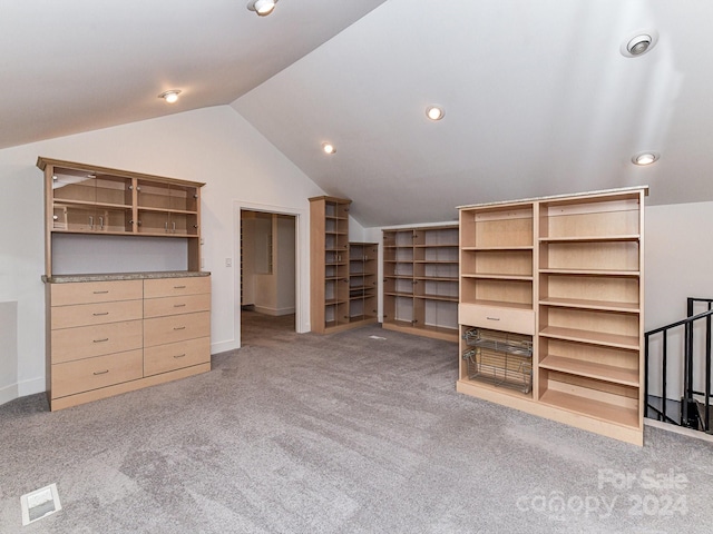 additional living space featuring light carpet, built in shelves, and vaulted ceiling