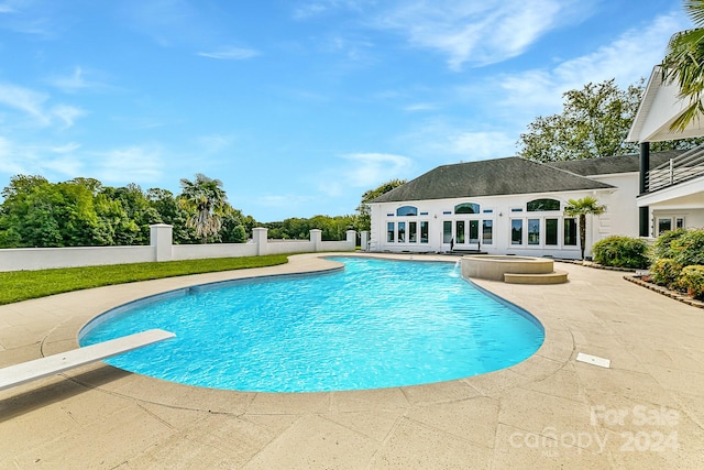 view of pool featuring a diving board, an outbuilding, and a patio