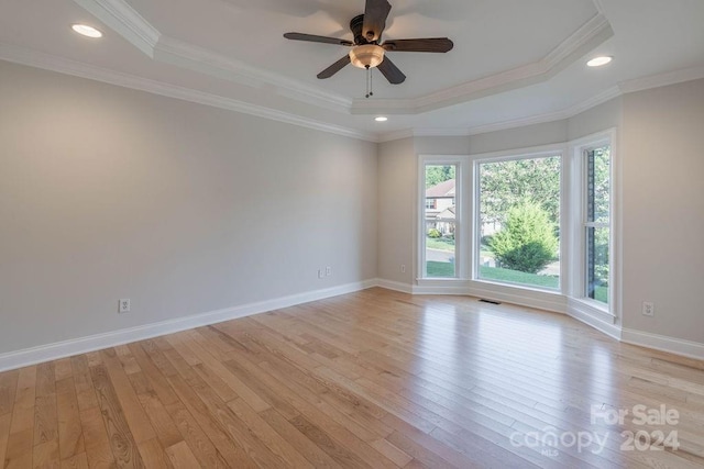 unfurnished room with a raised ceiling, light hardwood / wood-style flooring, ceiling fan, and ornamental molding