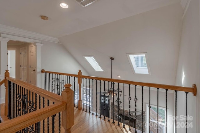 corridor with crown molding, vaulted ceiling with skylight, and light hardwood / wood-style floors