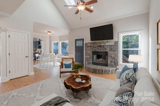 living room featuring ceiling fan, high vaulted ceiling, hardwood / wood-style floors, a fireplace, and ornamental molding