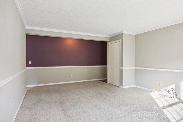 empty room with carpet floors, a textured ceiling, and crown molding