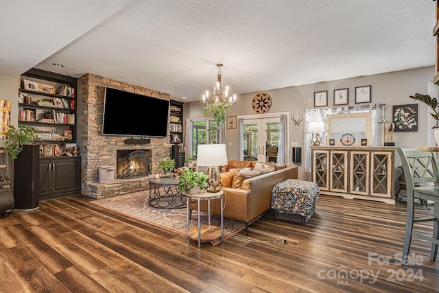 living room featuring a textured ceiling, french doors, a stone fireplace, dark hardwood / wood-style floors, and a notable chandelier