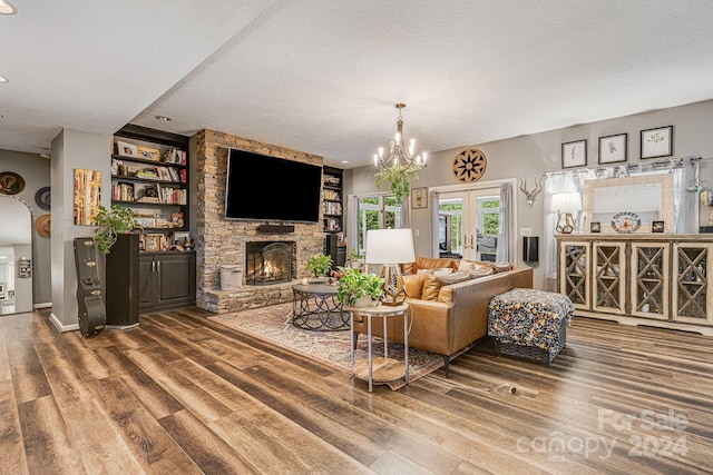 living room with a textured ceiling, wood-type flooring, french doors, an inviting chandelier, and a fireplace