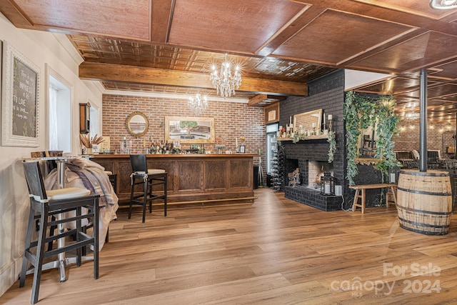 bar featuring a fireplace, beam ceiling, wood-type flooring, wood ceiling, and brick wall